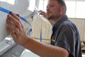 A Wipaire paint technician carefully applying masking tape following the striping design.